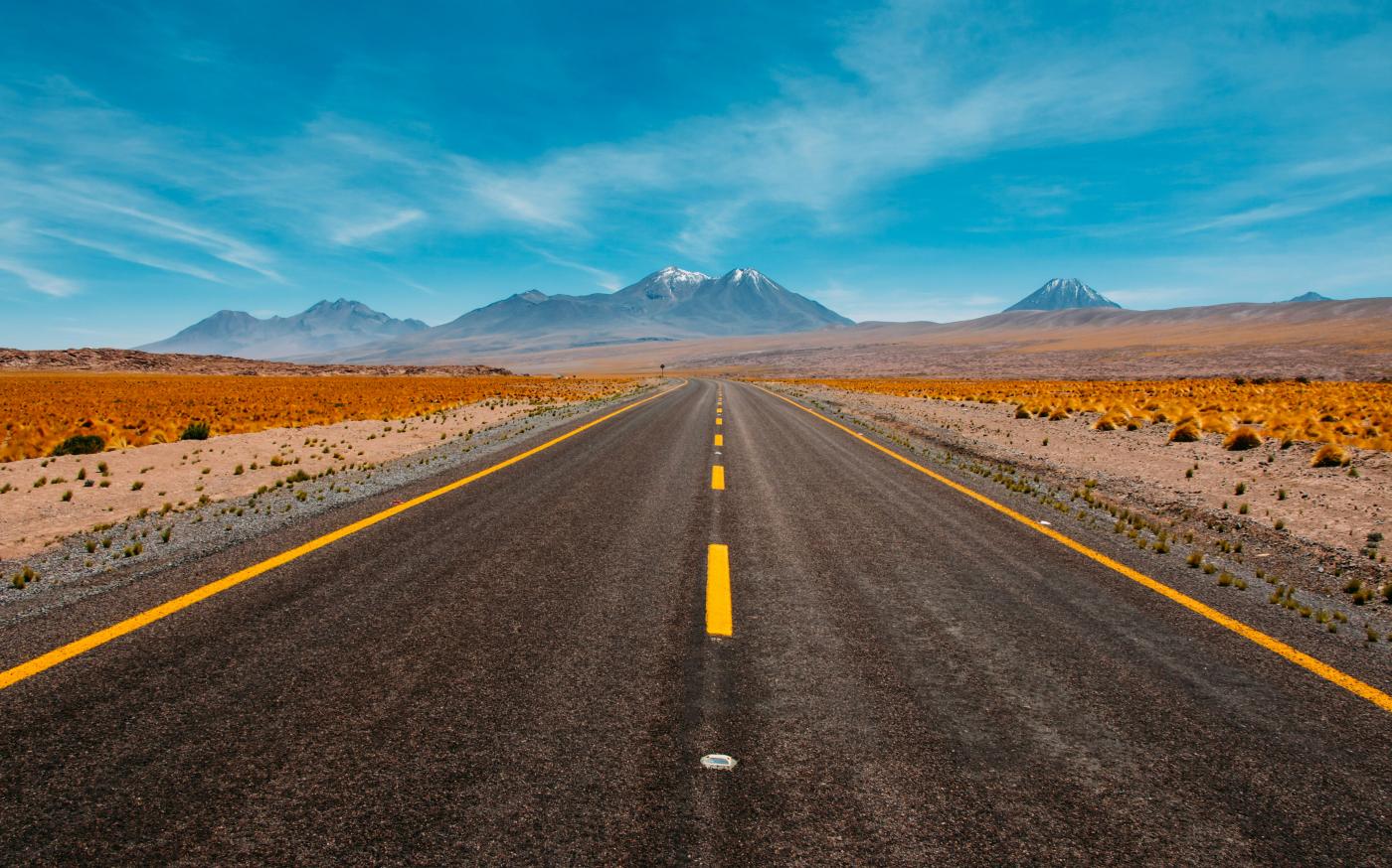 lone road going to mountains by Diego Jimenez courtesy of Unsplash.